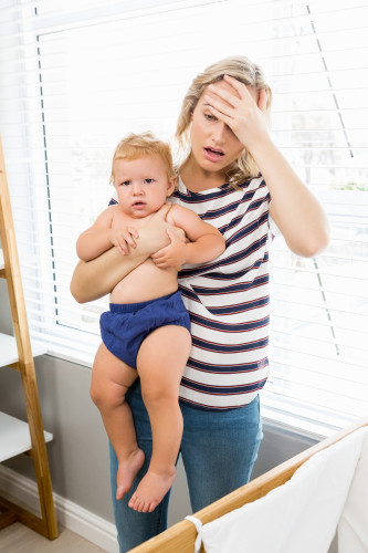 Stressed mother holding her baby boy at home